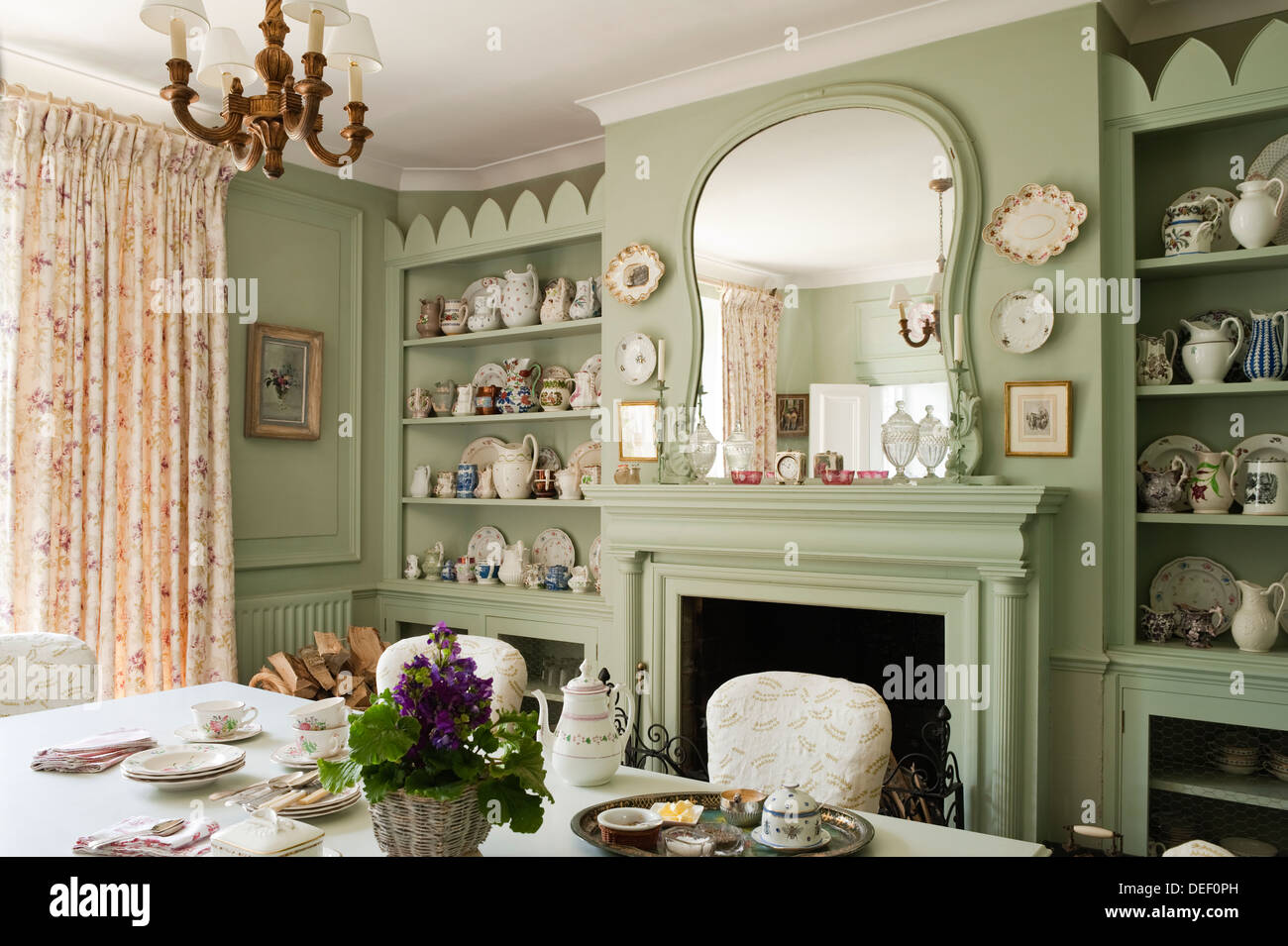 Country house dining room with pottery collection on recessed shelving painted in pastel green Stock Photo