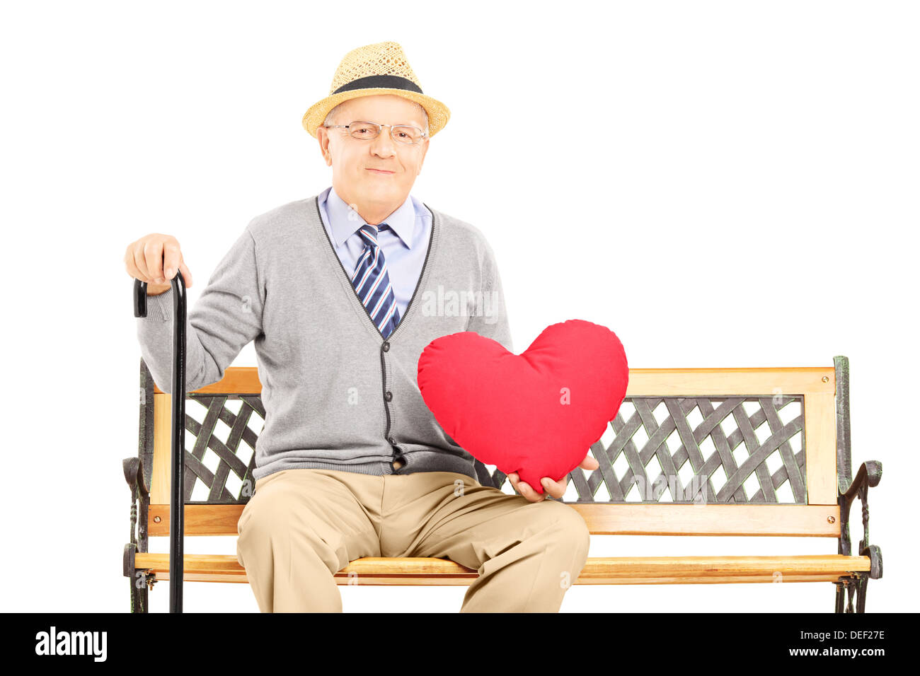 Senior man sitting on a wooden bench and holding a red heart Stock Photo