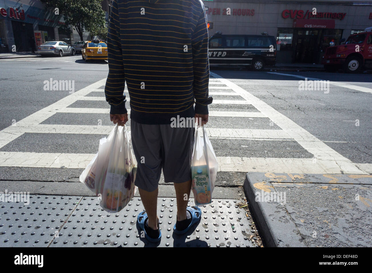 A shopper leaves a supermarket with a plastic bag holding his groceries in the New York neighborhood of Chelsea Stock Photo