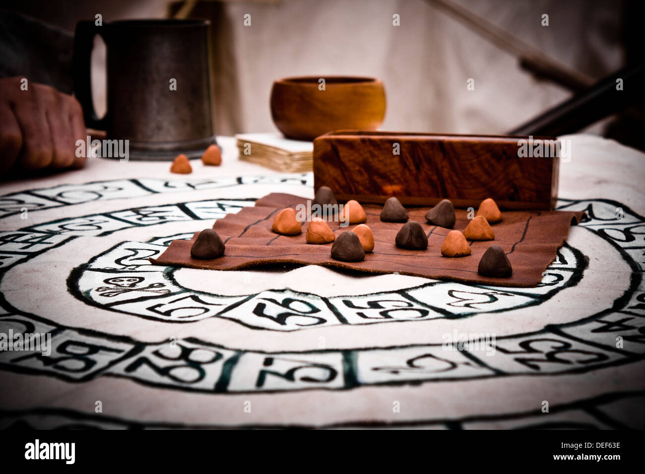 Traditional board game of Nine Mens Morris played in a re-enactment setting. Below is another old game of Royal Goose. Stock Photo