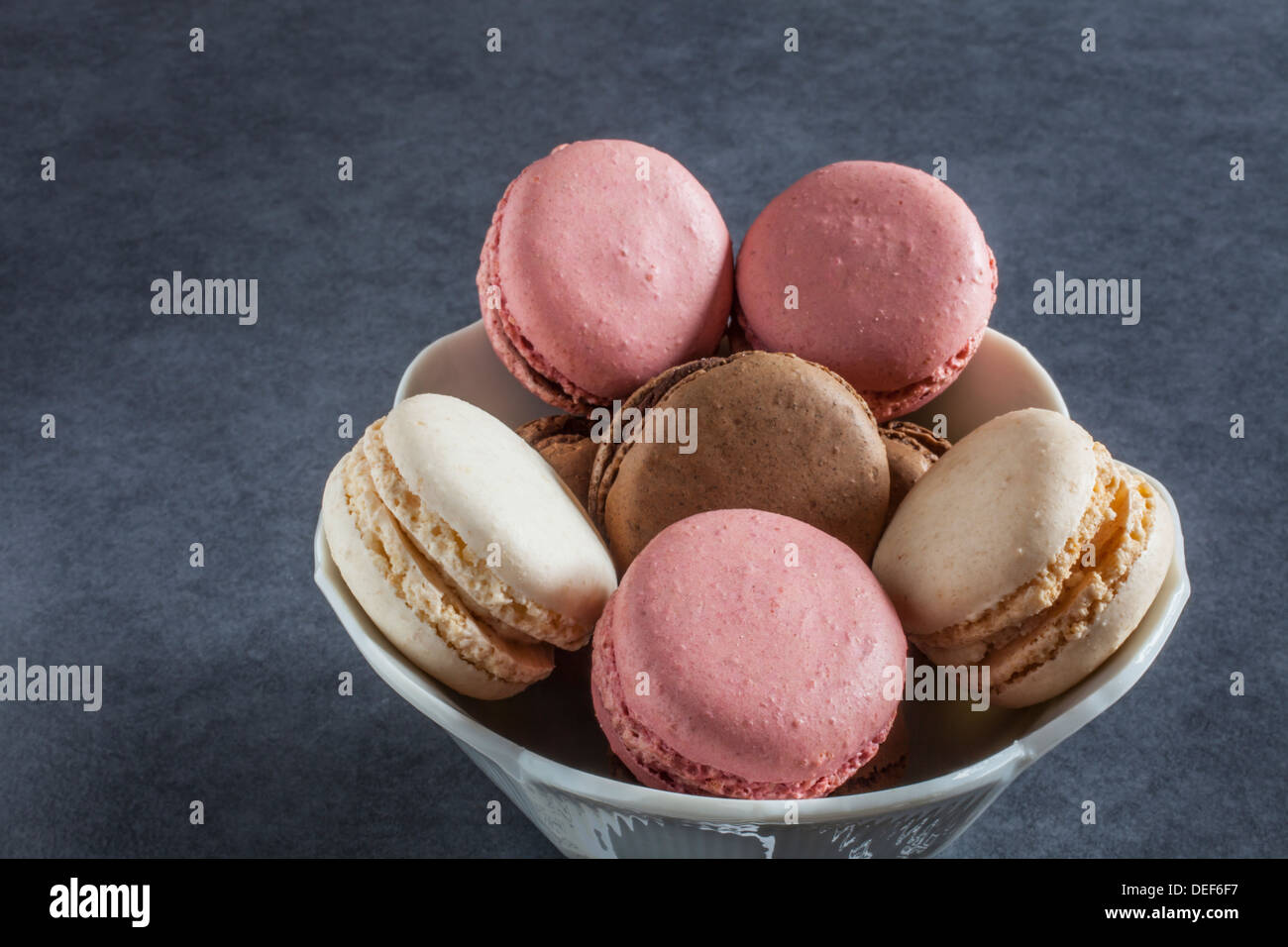 Strawberry/Raspberry, vanilla and chocolate flavoured French-style macaroons in a bowl Stock Photo