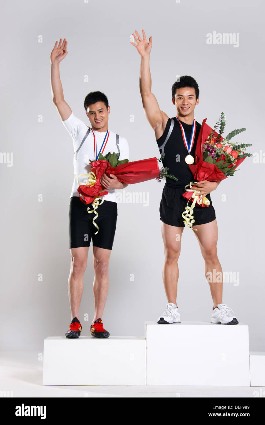 Young male athletes holding trophy and flowers Stock Photo Alamy