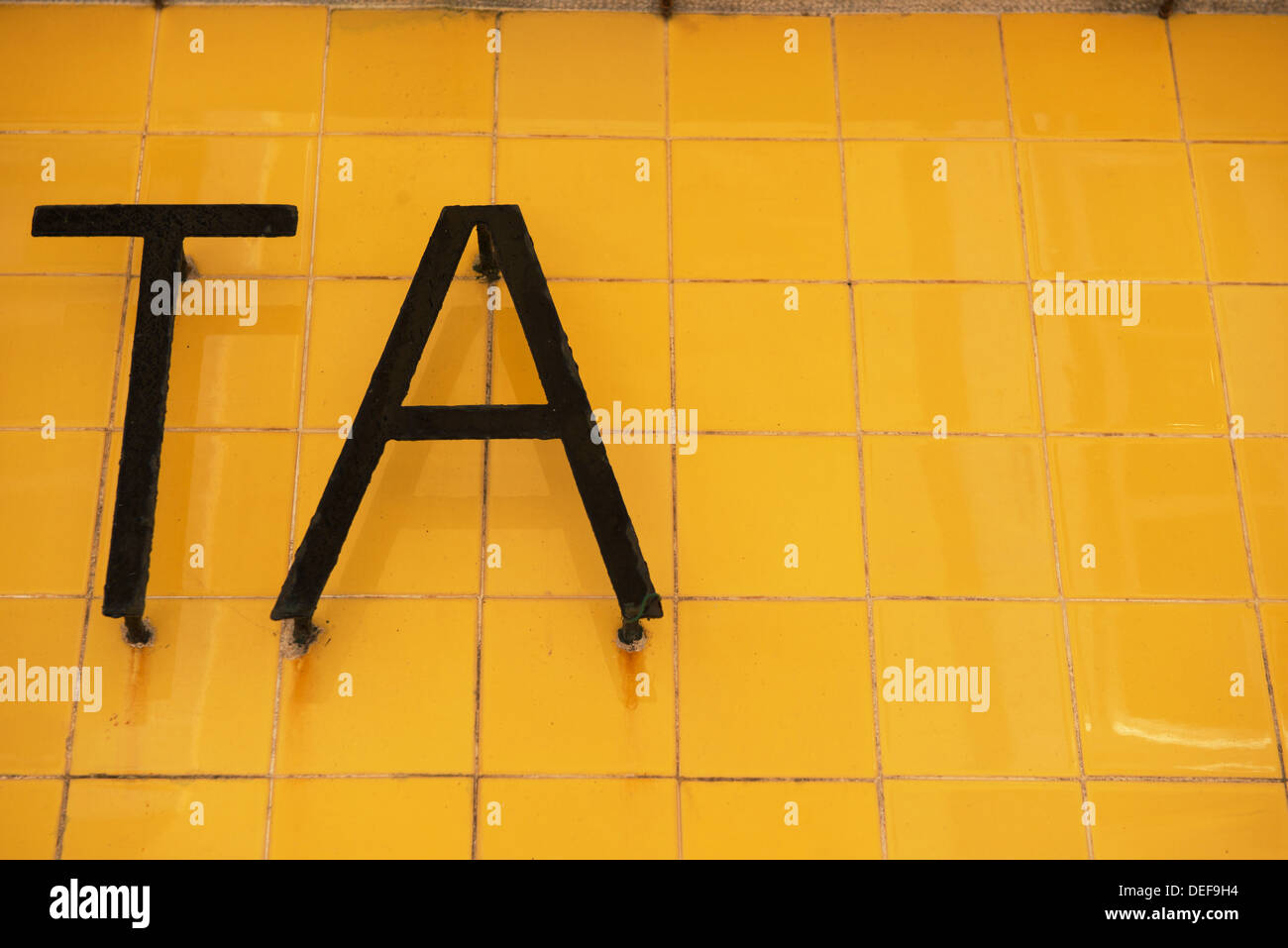 Ta, written with metal letters on a yellow tiled wall Stock Photo