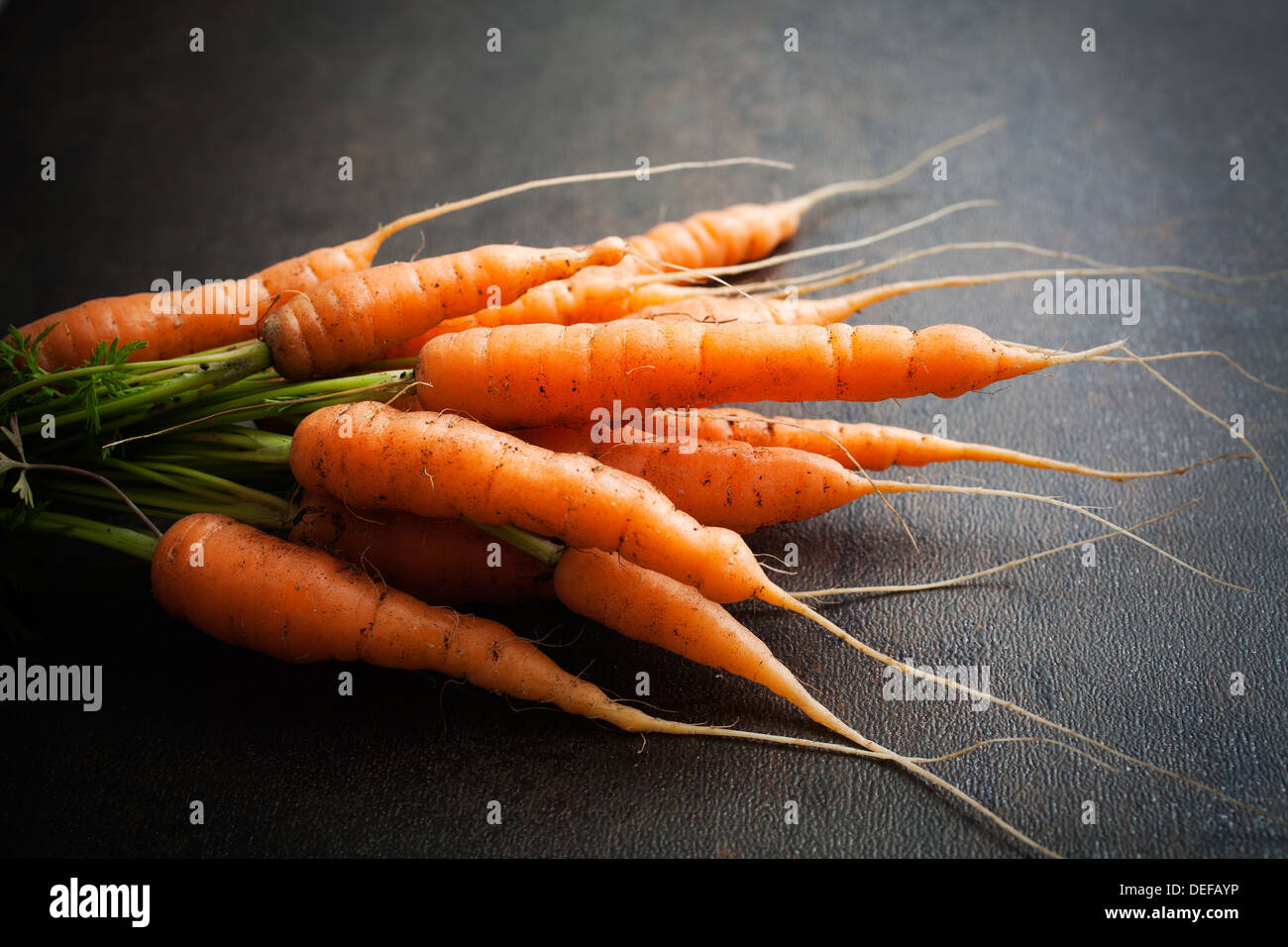 Bunch of fresh carrots on dark background Stock Photo