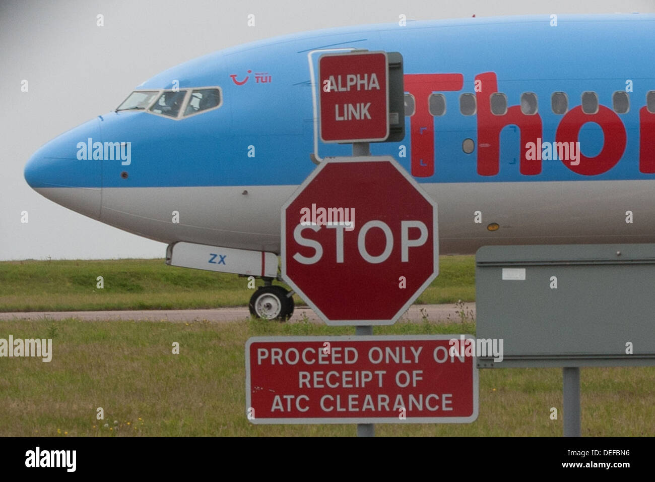 Airliner taxiing behind vehicle 'stop' sign at Luton airport Stock Photo