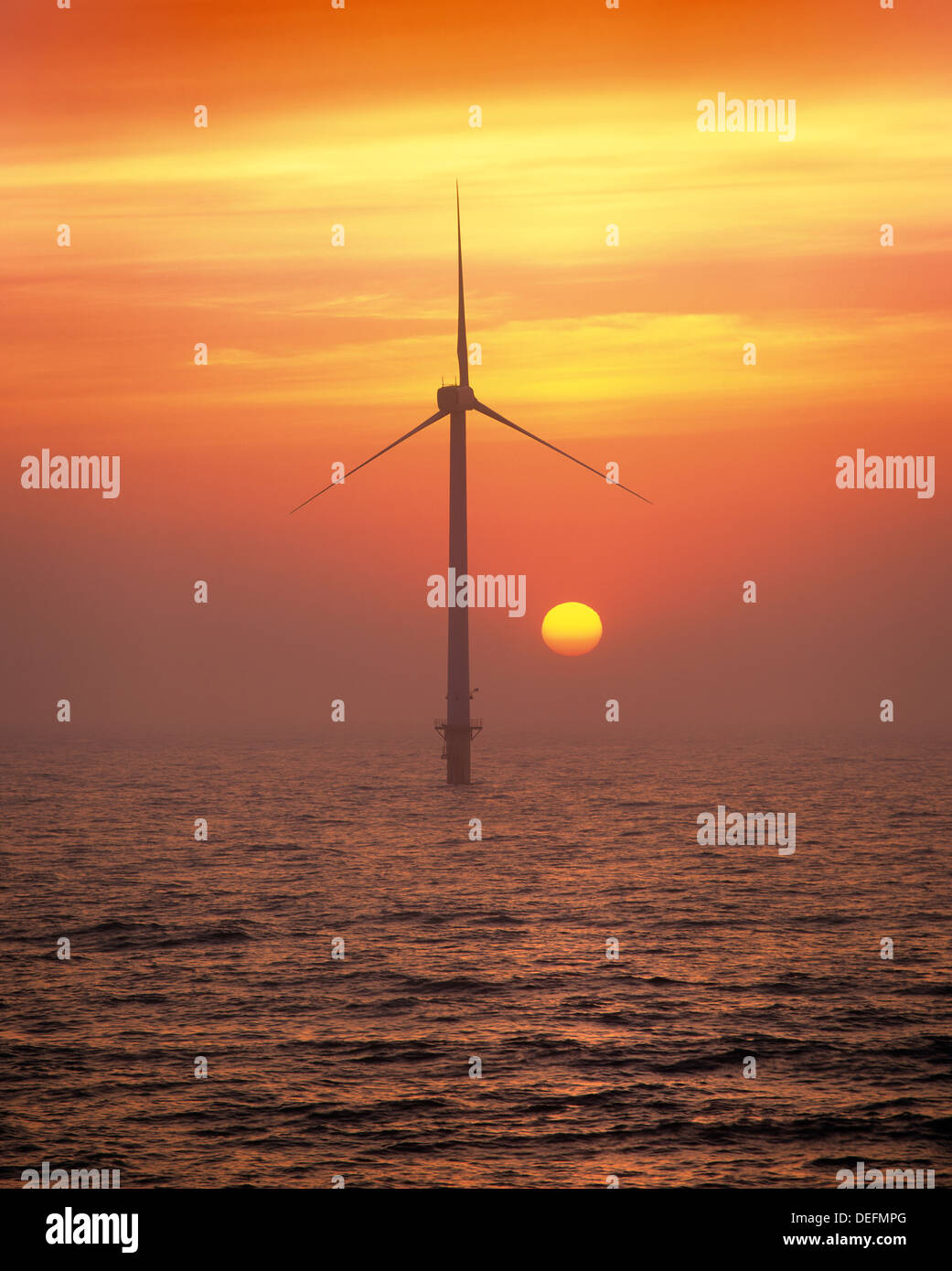 The dawn of a new age? Sunrise behind one of the wind turbines in the Blyth wind farm - Britain's first off shore wind turbines. Stock Photo