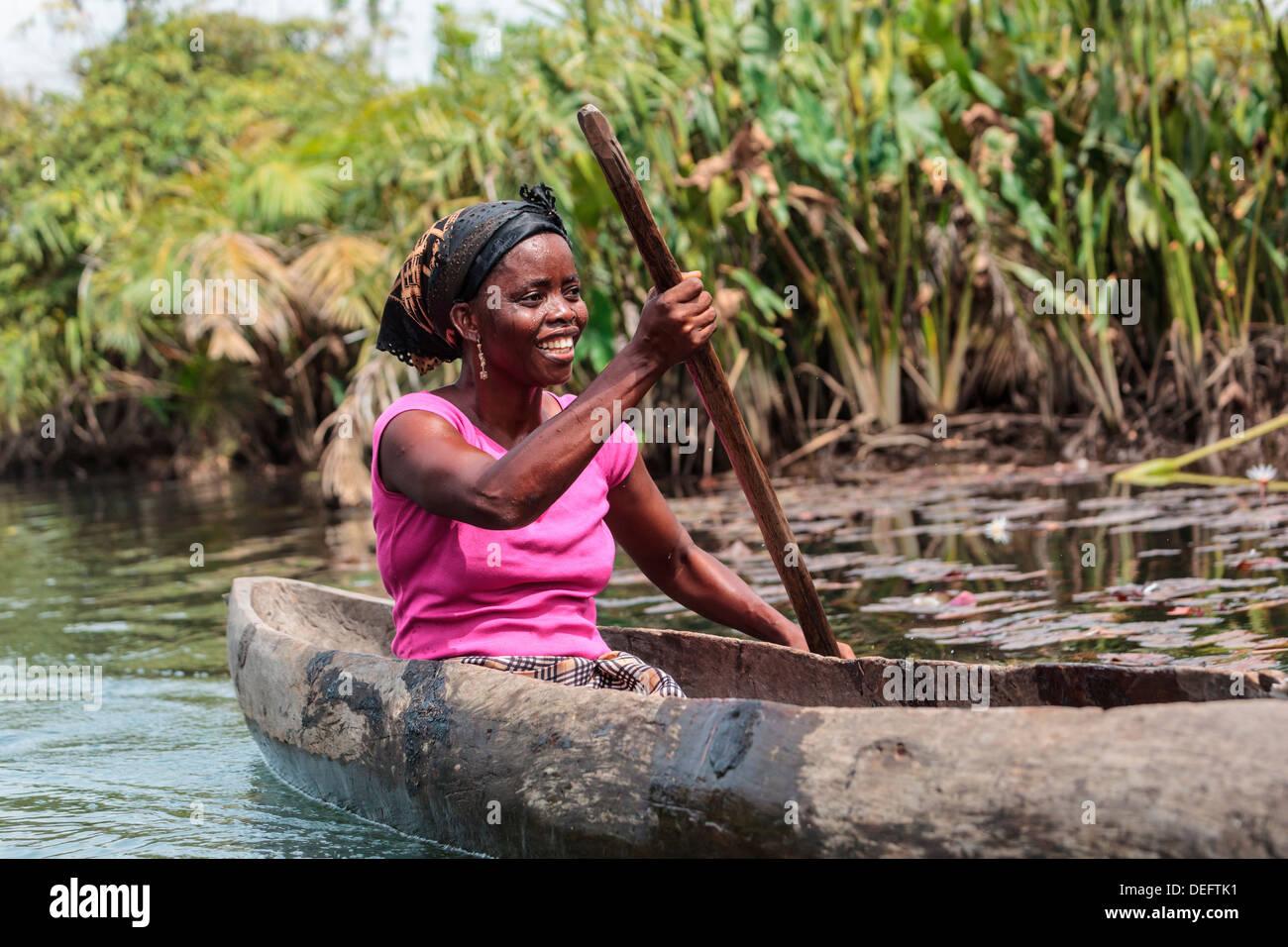 Africa, Liberia, Monrovia. Woman rowing traditional pirogue down Du River. Stock Photo