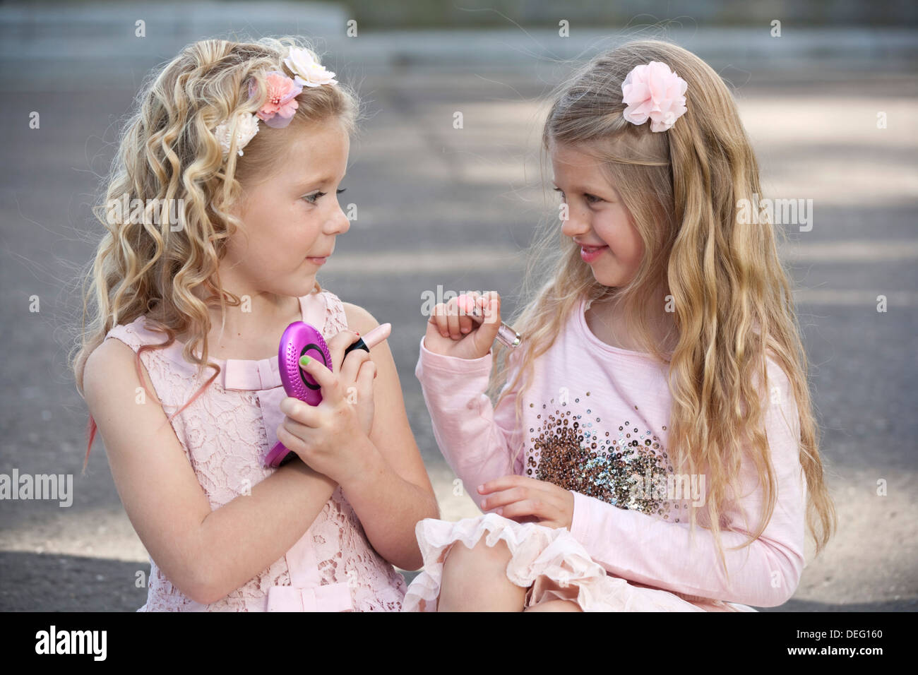 Two young preteen girls wearing pink and putting make up on. Stock Photo