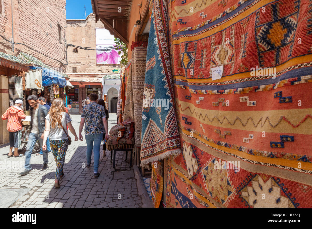 Tourists and locals walking alongside traditional rugs in the Medina's souks, Marrakech, Morocco, North Africa, Africa Stock Photo