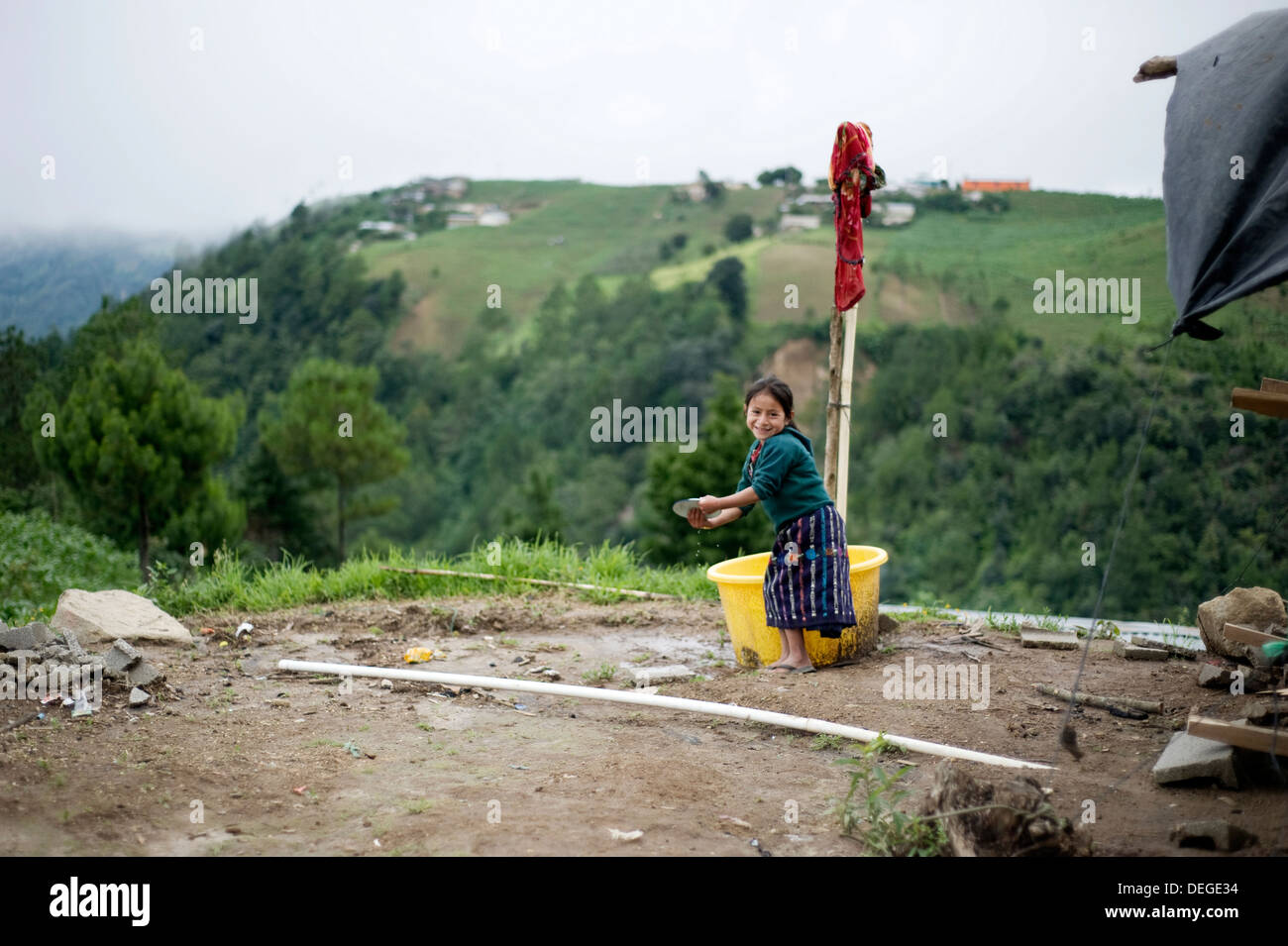 A Guatemalan girl in traditional Maya clothing washes dishes outside in Caserio Panuca, Solola, Guatemala. Stock Photo