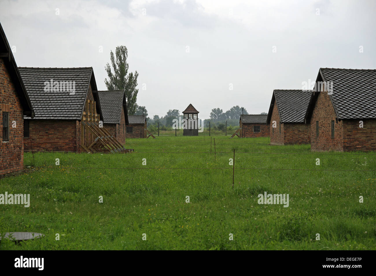 Prisoner huts where Jews were kept before going to the gas chambers and the guards watch tower in the distance. Stock Photo