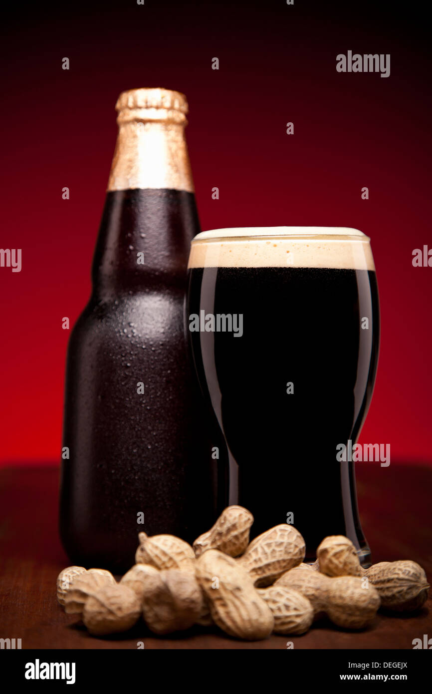 A glass, a bottle of beer and a hand full of peanuts. Stock Photo