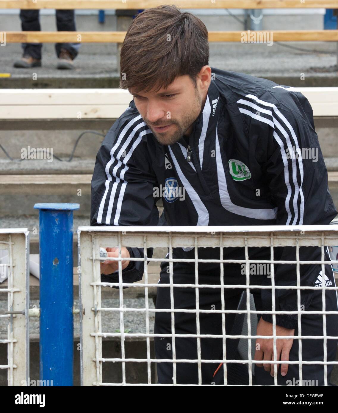 Diego Ribas da Cunha of VfL Wolfsburg paints the fence of the TSG Calbe Heger stadium in Calbe, Germany, 18 September 2013. Three months after floodwaters damaged the stadium VfL Wolfsburg helps the club from Calbe. Photo: PETER ENDING Stock Photo