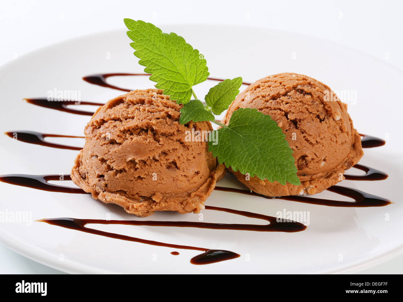 Scoops of brown ice cream with chocolate syrup Stock Photo Alamy