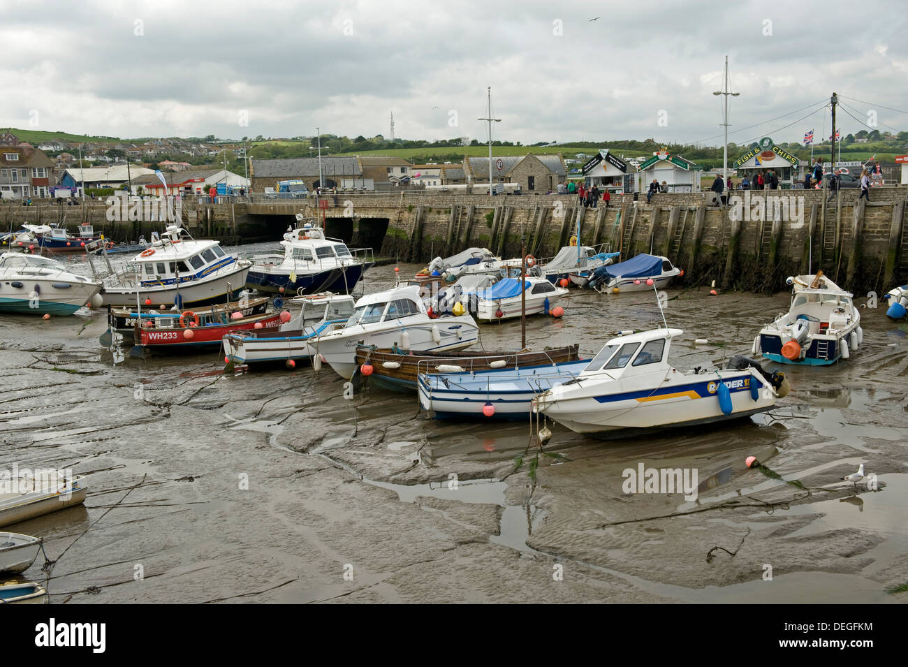 Fishing and leisure boats resting on the mud at low tide in West Bay Harbour, near Bridport in Dorset, May Stock Photo