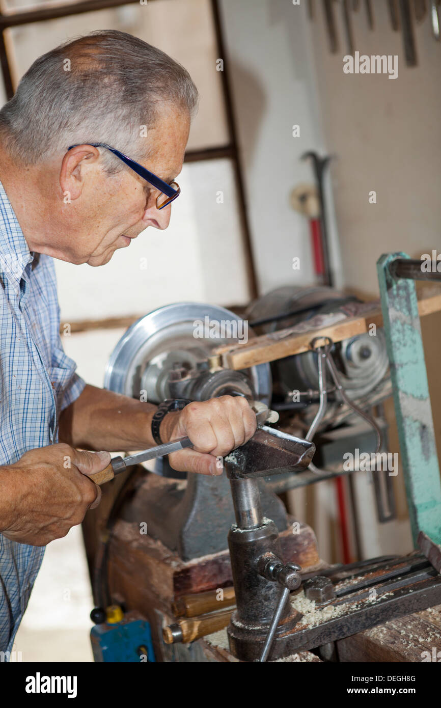 Old senior craftsman working on the lathe in his workshop in Brianza near Milan, Italy Stock Photo