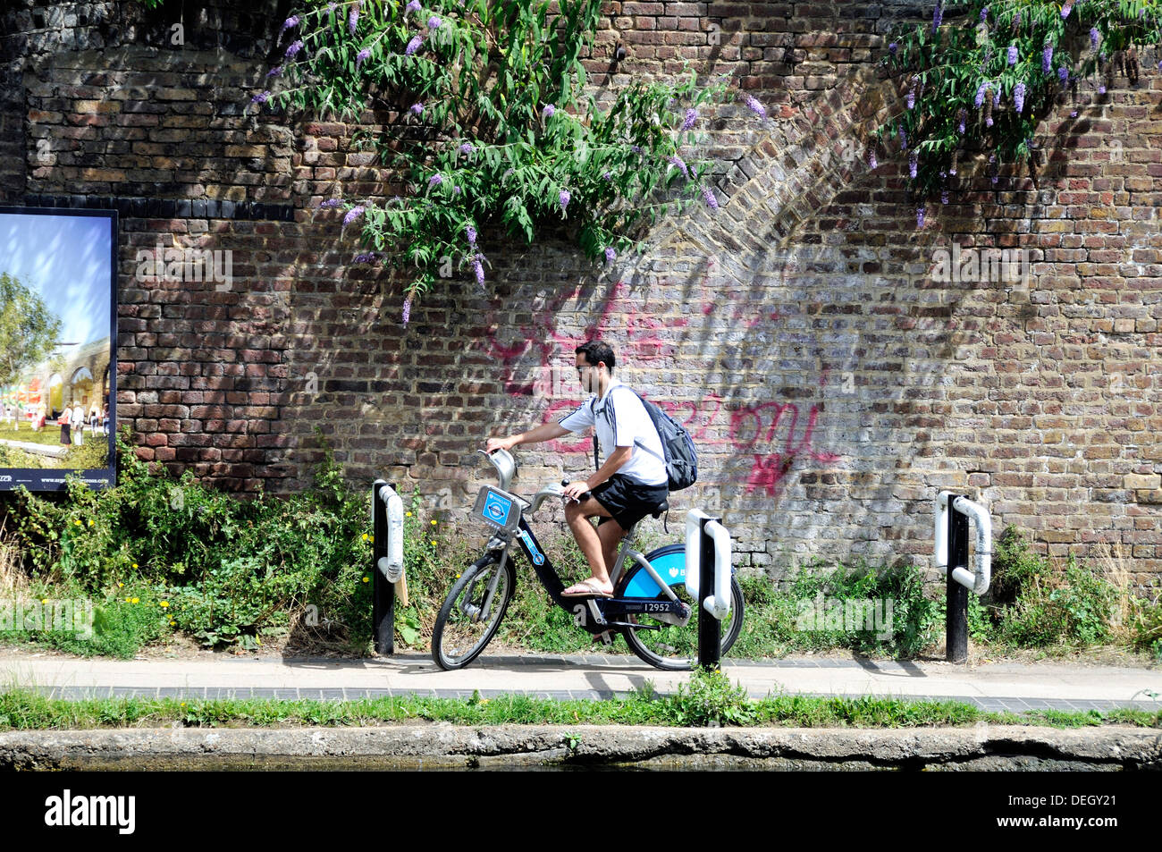 Male cyclist on Barclays Cycle or Boris Bike negotiating a chicane installed on the Regent's Canal towpath to slow down cyclists Stock Photo