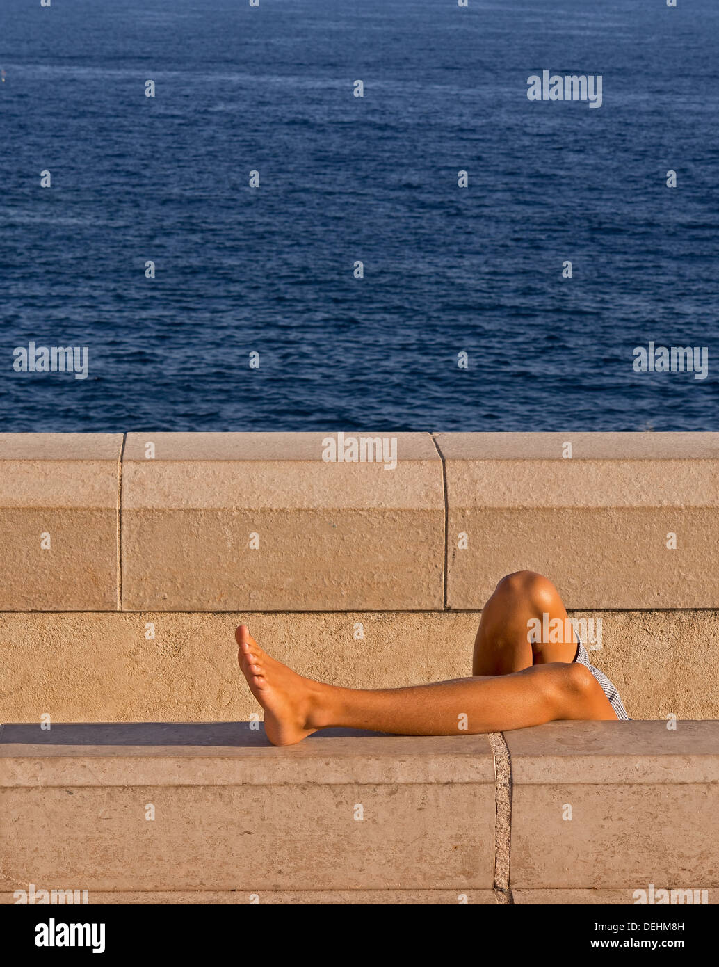 Young man sunbathing behind wall - unusual view Stock Photo