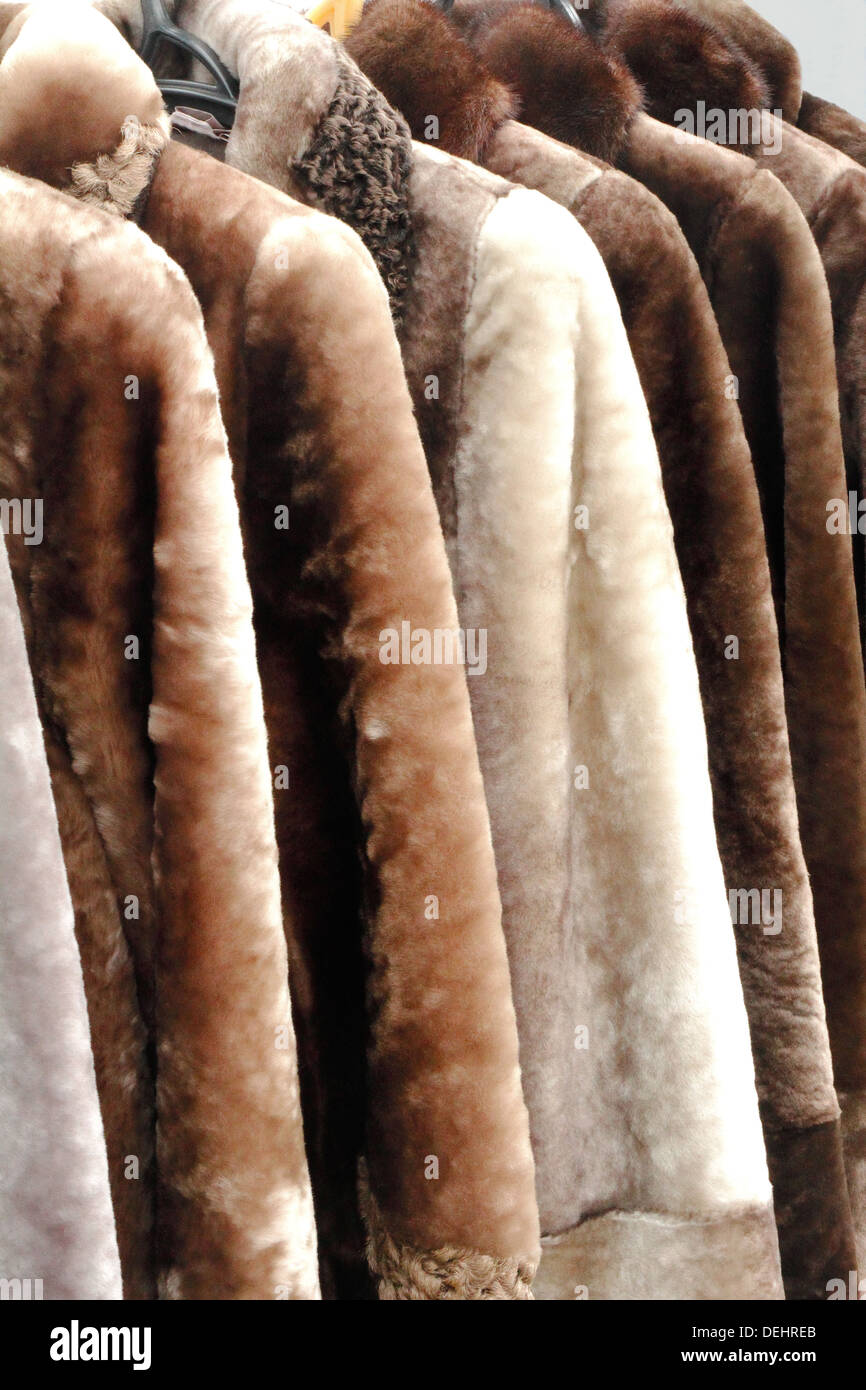 Beautiful warm womens coats made of natural fur hang in store for sale. Stock Photo