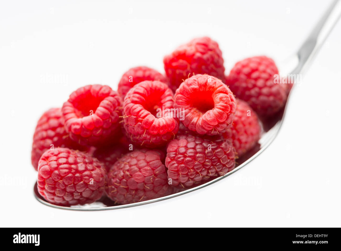 A handful of delicious, fresh, healthy and appetizing raspberries arranged on a large silver spoon Stock Photo