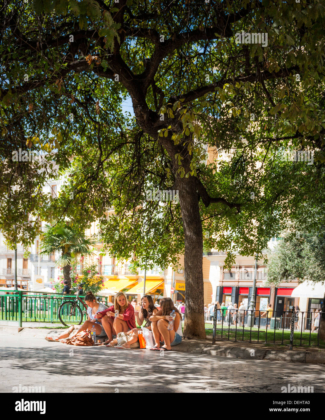 Four young girls swap stories and share a refreshing drink of water after a day's shopping in a sweltering Valencia in Spain. Stock Photo