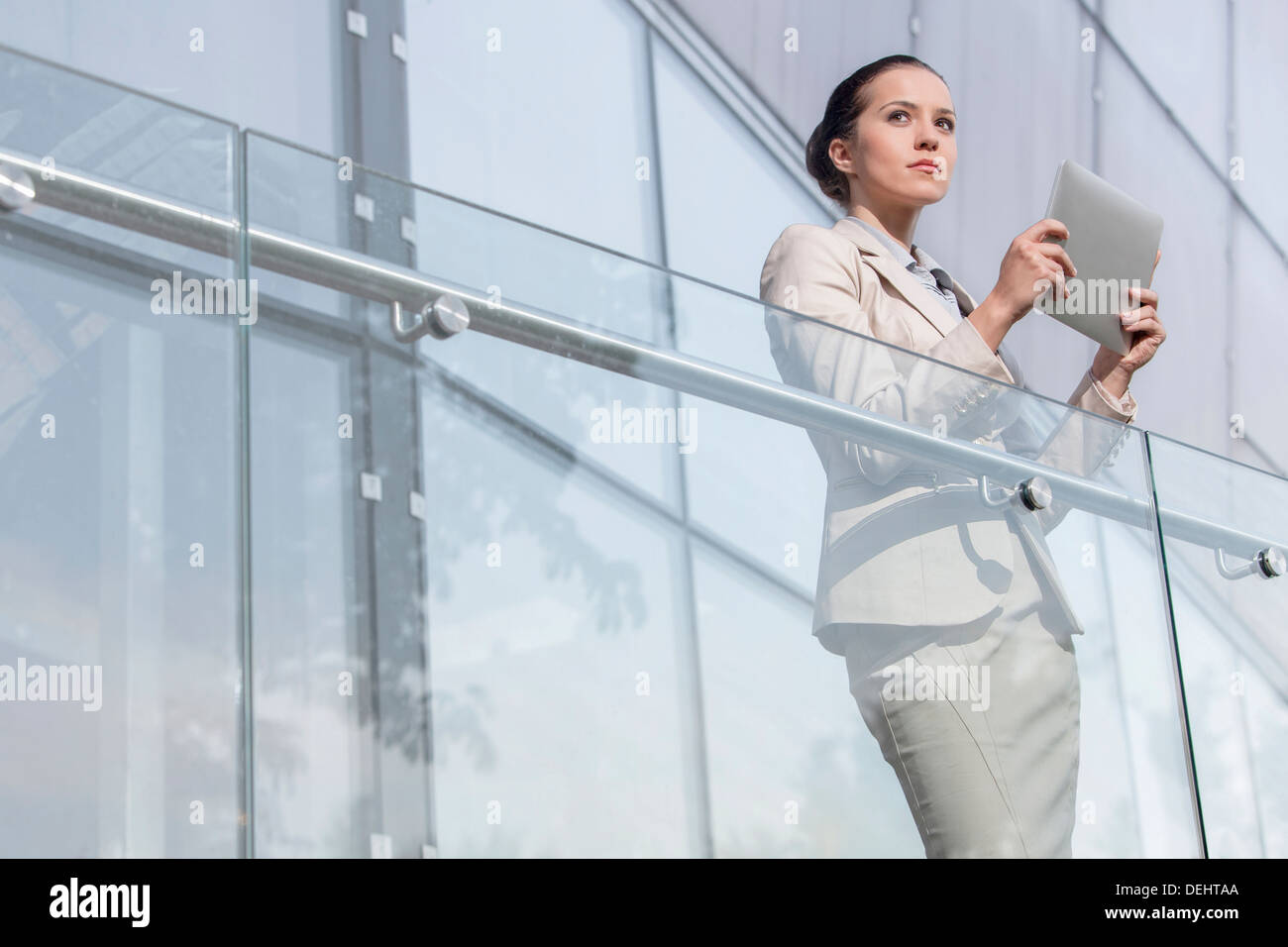 Beautiful young businesswoman holding tablet computer office railing ...