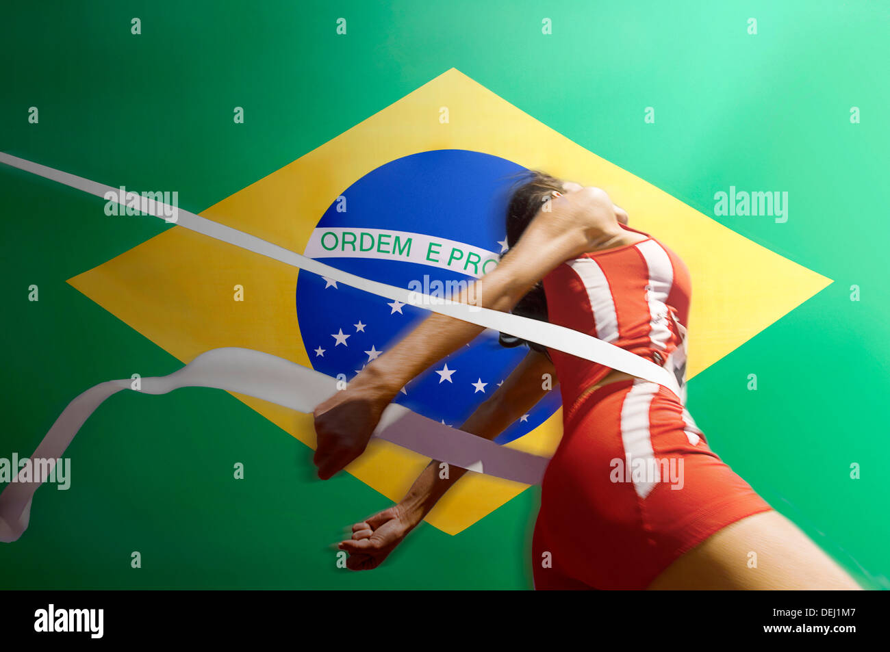 Runner Breaking through the finishing line tape over Brazilian flag Stock Photo