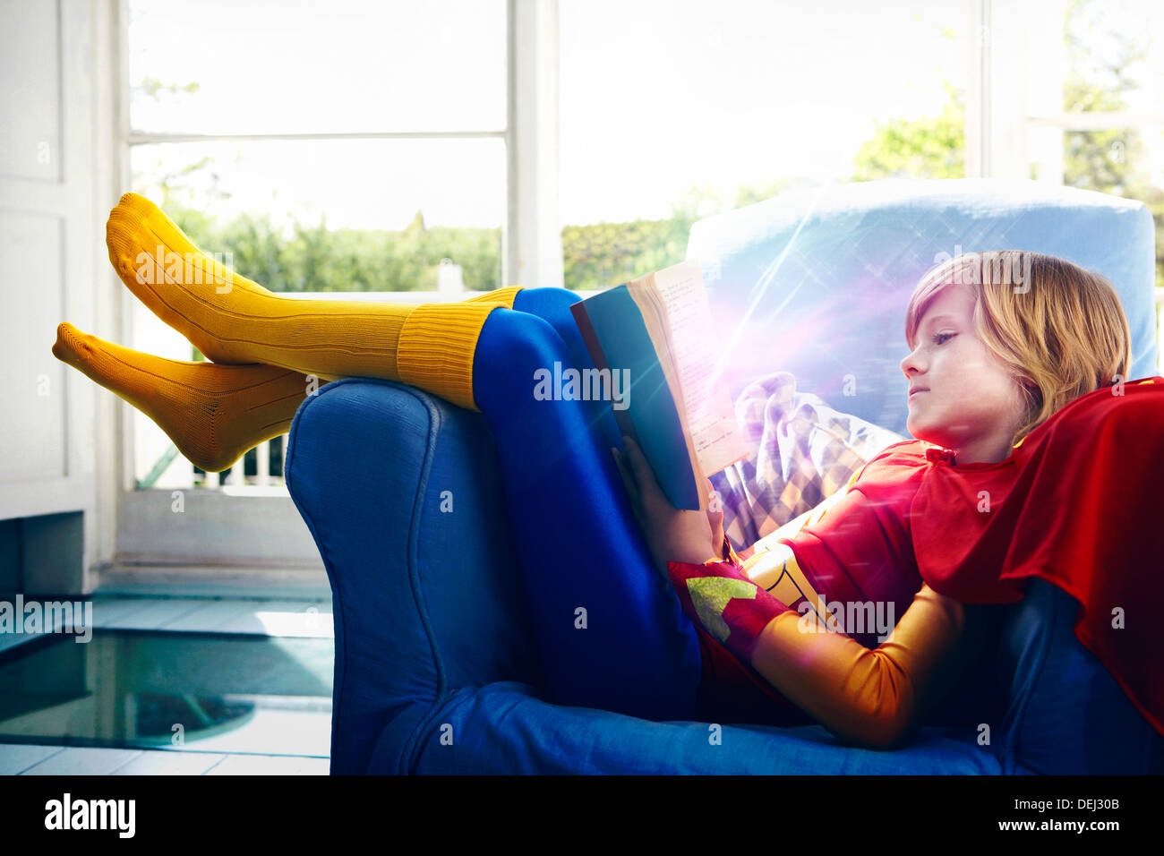 Little boy dressed as a super hero reading a book Stock Photo