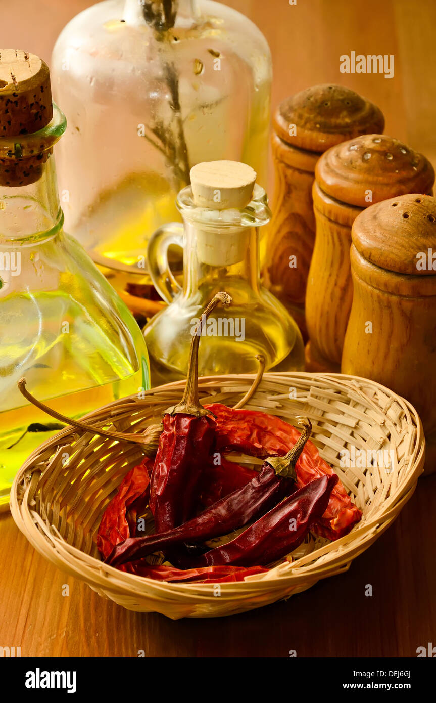 basket with dried chili peppers, olive oil and condiments Stock Photo