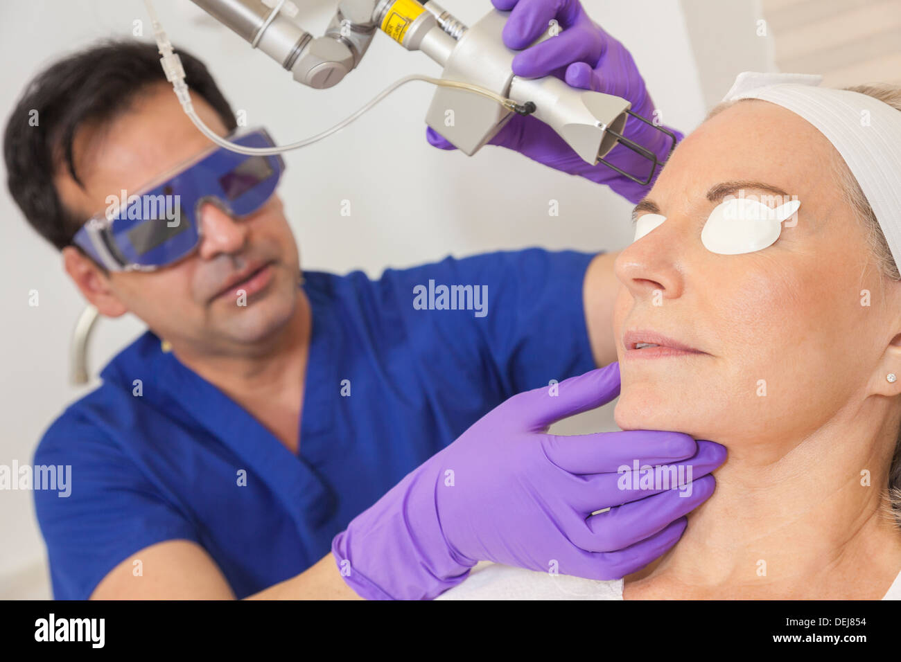 A cosmetic surgeon doctor giving fractional CO2 laser skin treatment to the face of a senior female woman patient Stock Photo