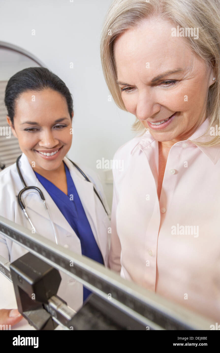 A senior woman being weighed on scales by female latina hispanic doctor nutritionist Stock Photo