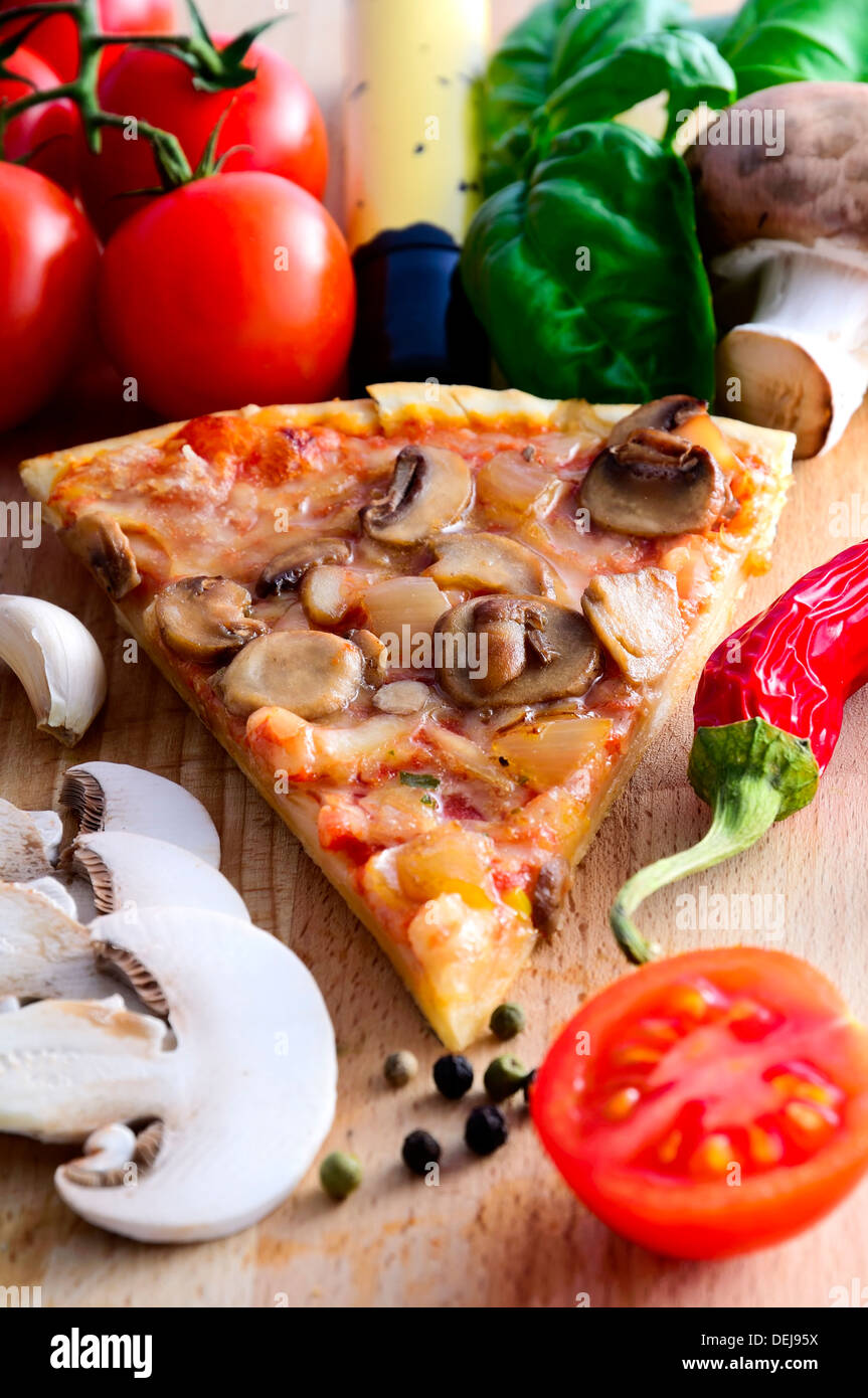 pizza slice and ingredients on a wooden background Stock Photo