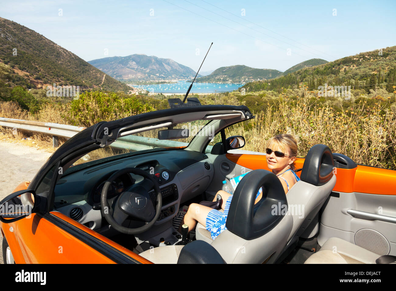Lady woman in open top Citroen cabriolet passenger overlooking Nidri harbour harbor Lefkas Lefkada Greek Island Greece Nydri Stock Photo