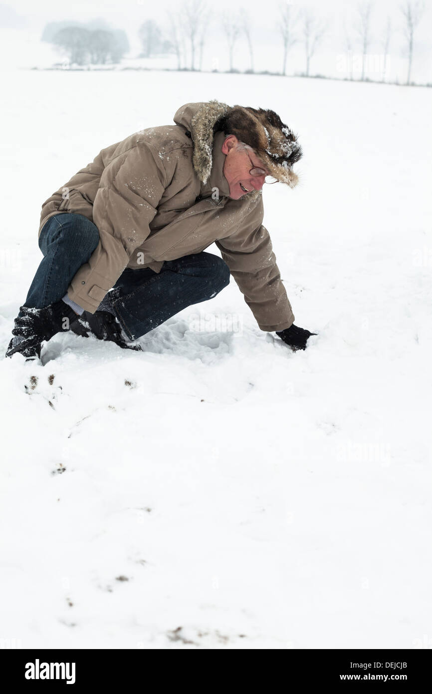 Senior man with injured leg on snow. Stock Photo