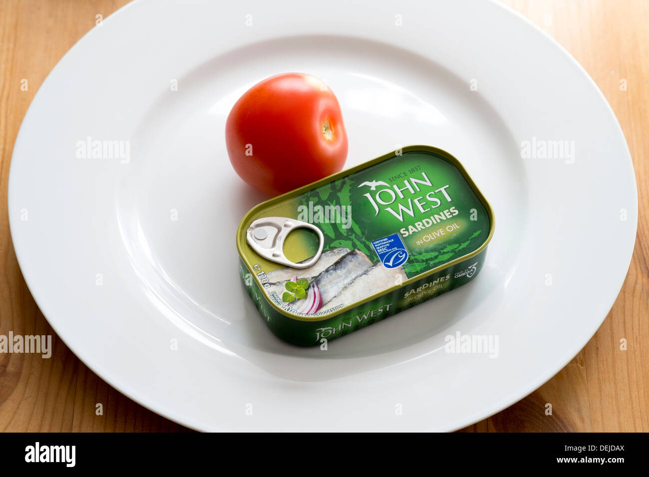 Ring pull can of John West Sardines in Olive oil with red Tomato on white china plate Stock