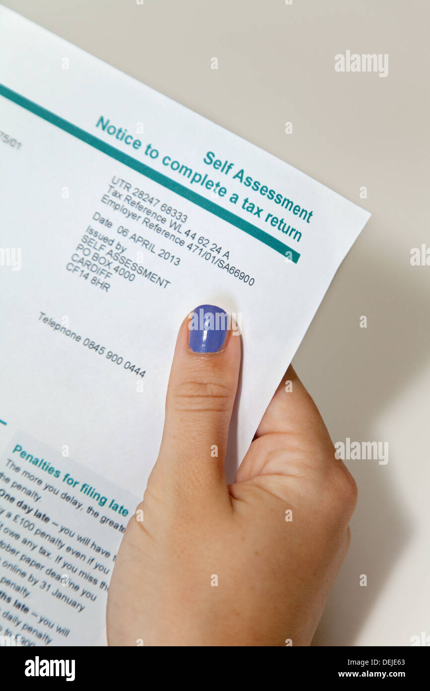 Womans hand holding a Self Assessment Tax return form, UK Stock Photo