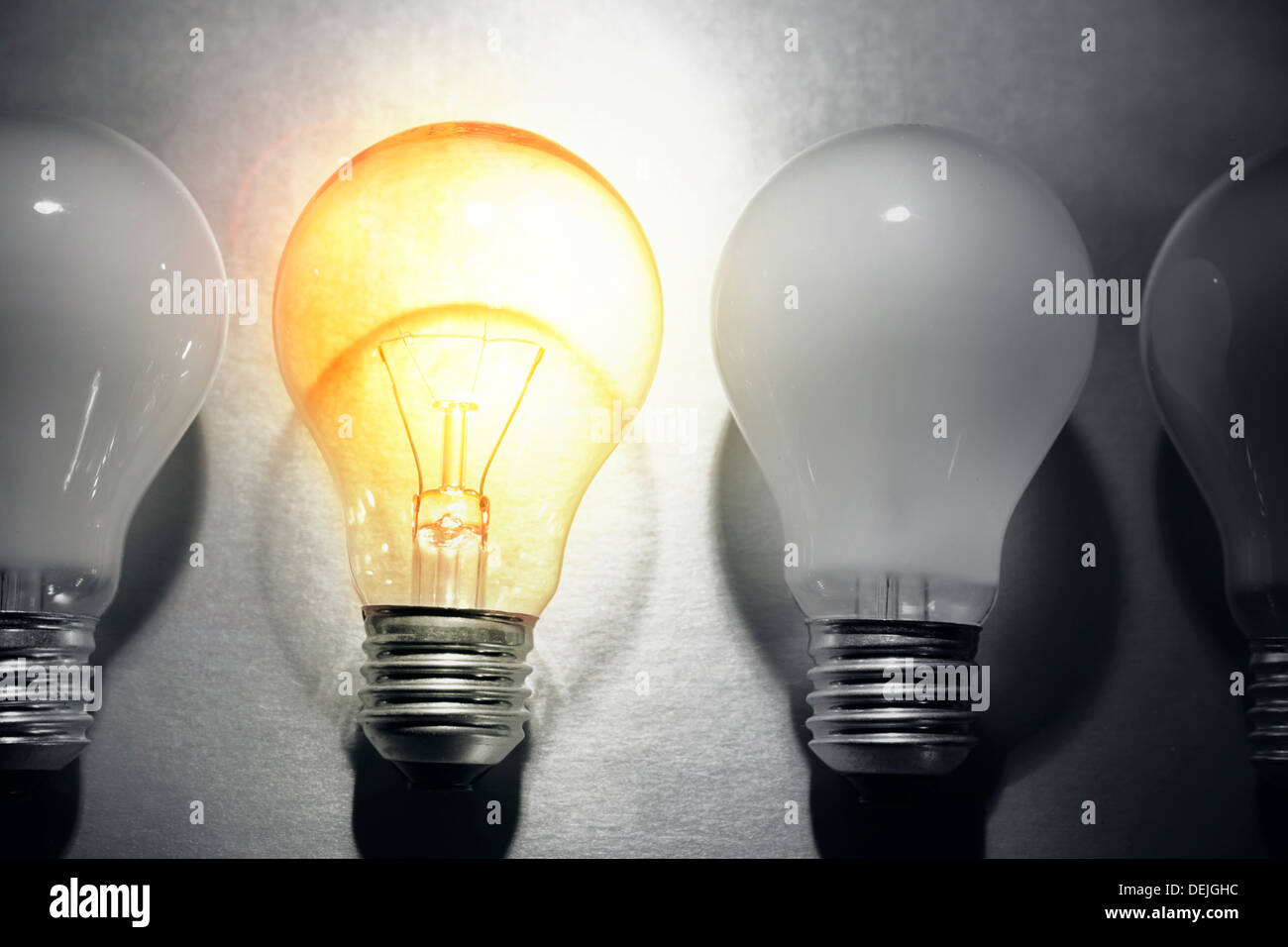 One bright bulb in line of dull light bulbs. Standing out concept Stock Photo