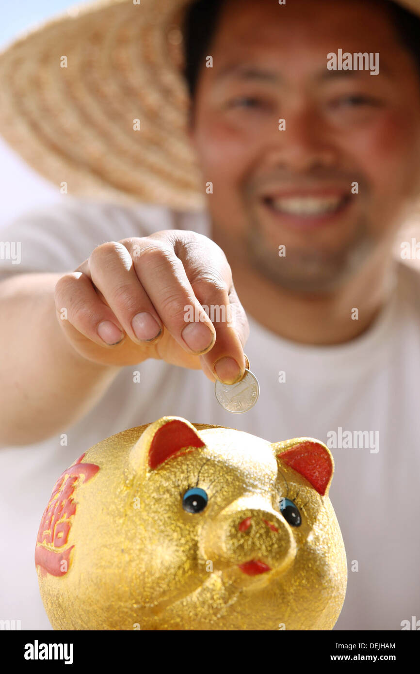 Farmer putting coin in piggy bank Stock Photo - Alamy