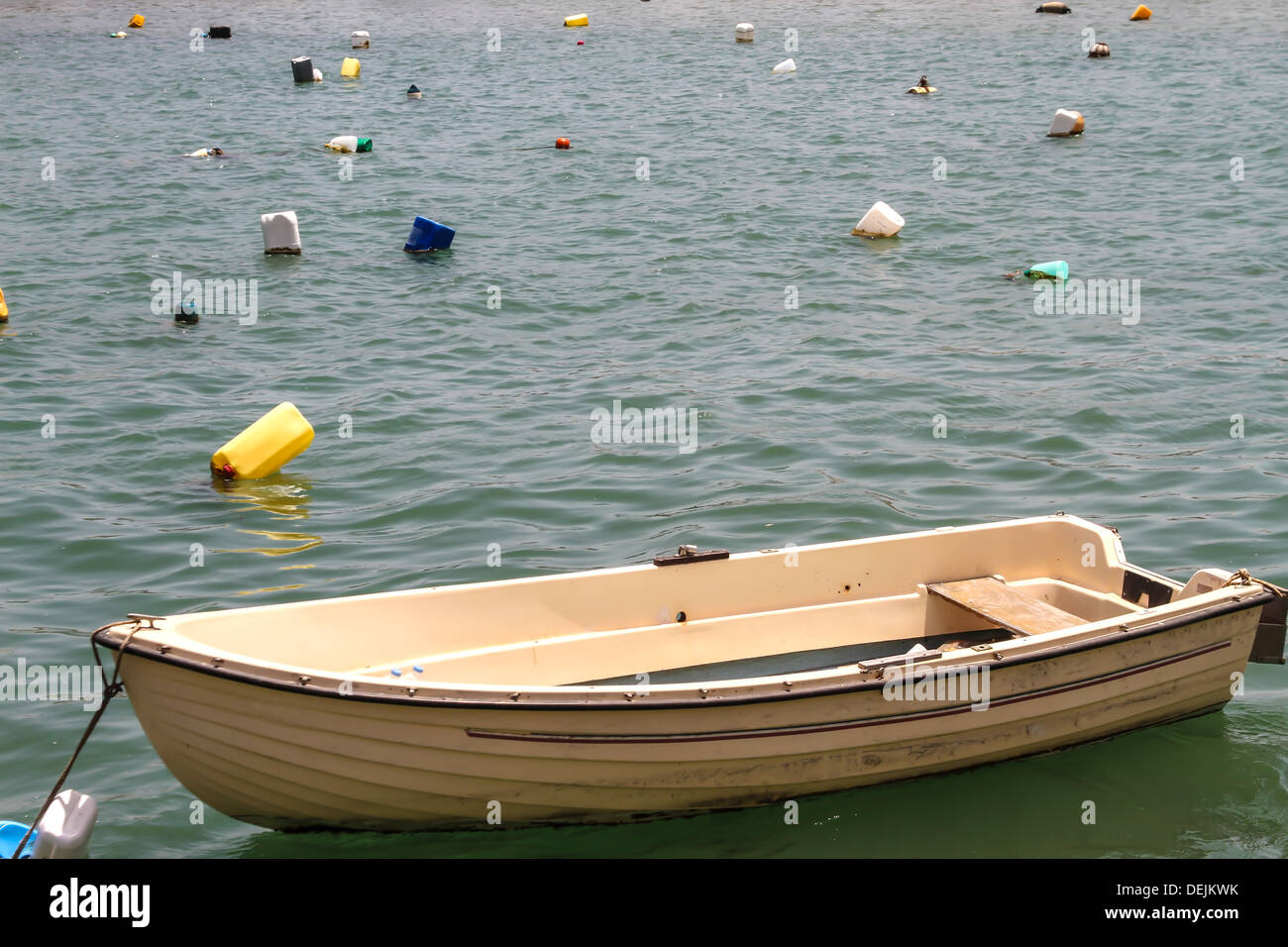 Wooden rowboat in the sea surrounded by plastic containers Stock Photo
