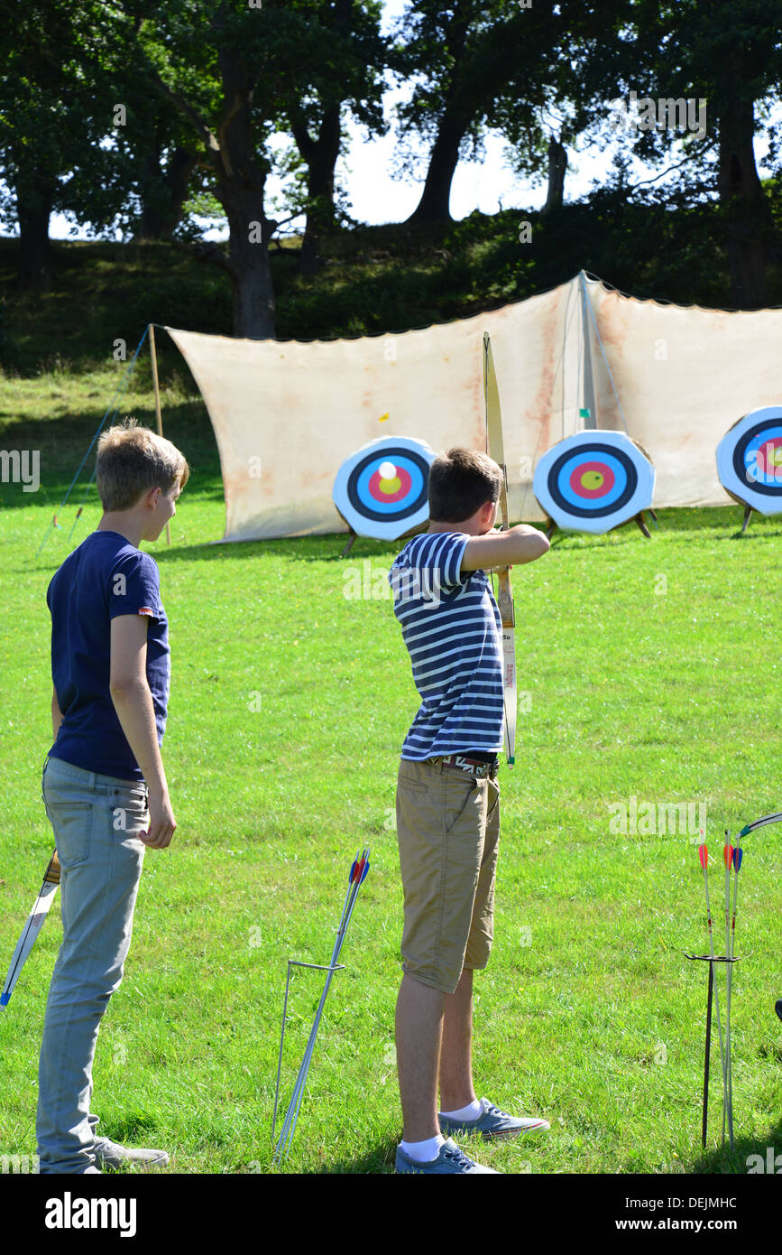 Young boys trying archery at The Dunster Agricultural Show, Dunster Castle Lawns, Dunster, Somerset, England, United Kingdom Stock Photo