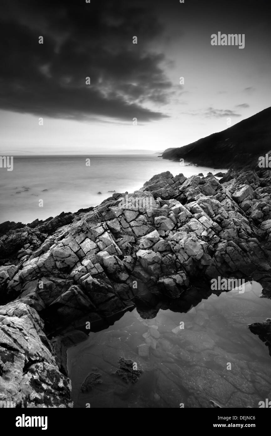 Late winter sunset at the Gower, Langland Bay in high winds with rocky foreshore and calm sea Stock Photo