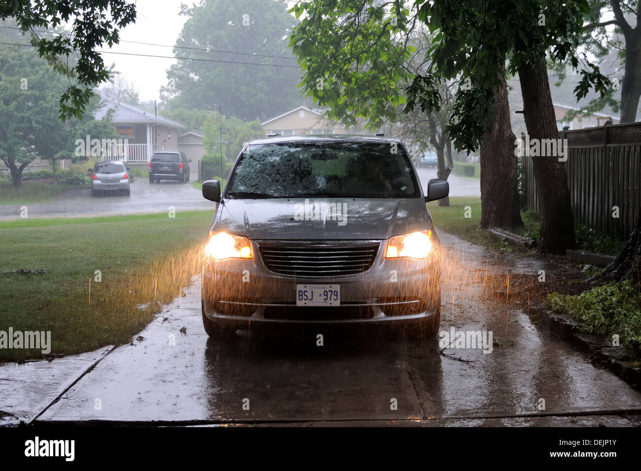 Car on a driveway with lights on in thunder storm in Canada Stock Photo