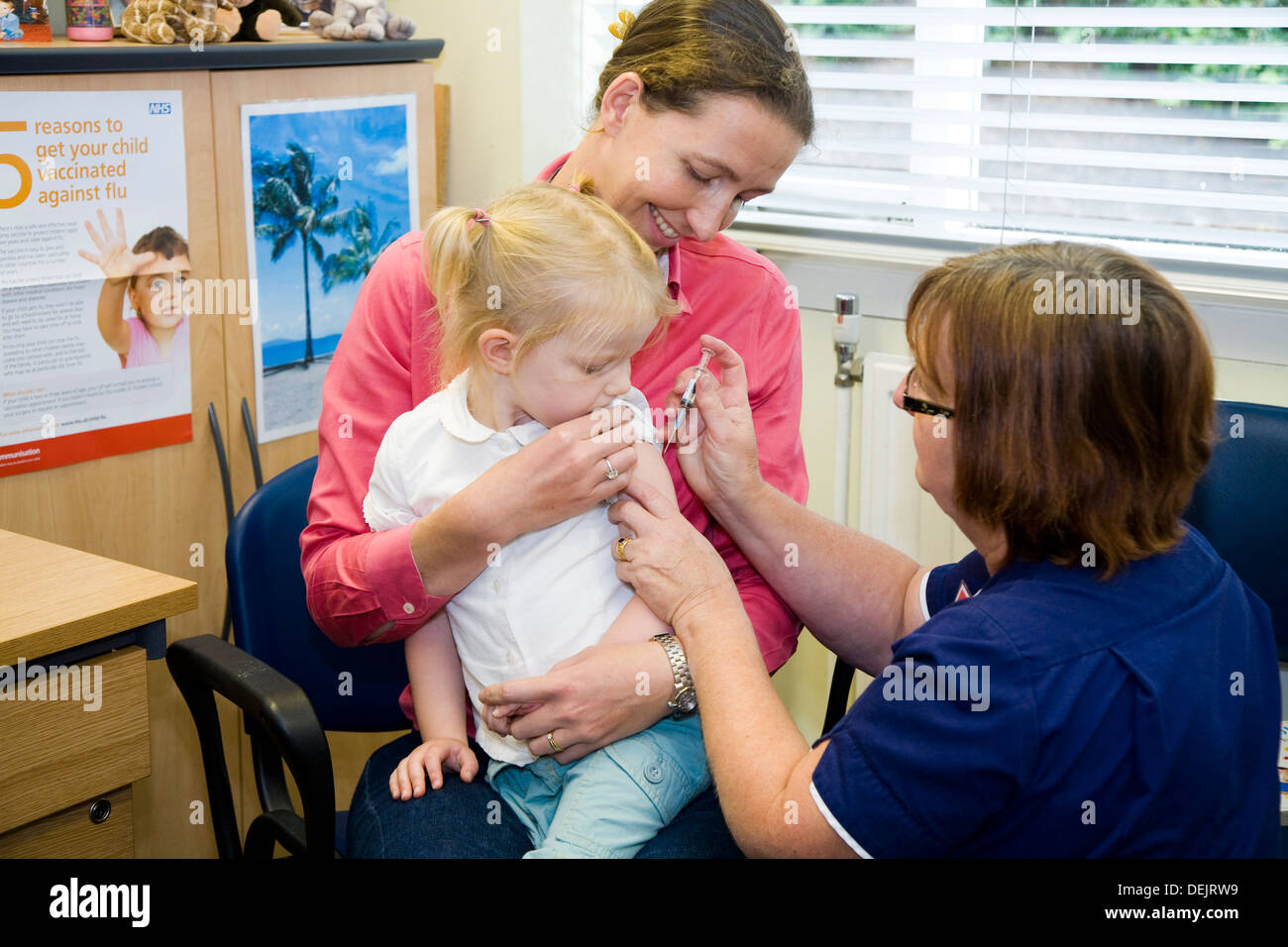 Nurse giving NHS 4-in-1 pre-school booster & MMR second dose immunisation / inoculation / jab to a three 3 year old child / girl / kid. Stock Photo