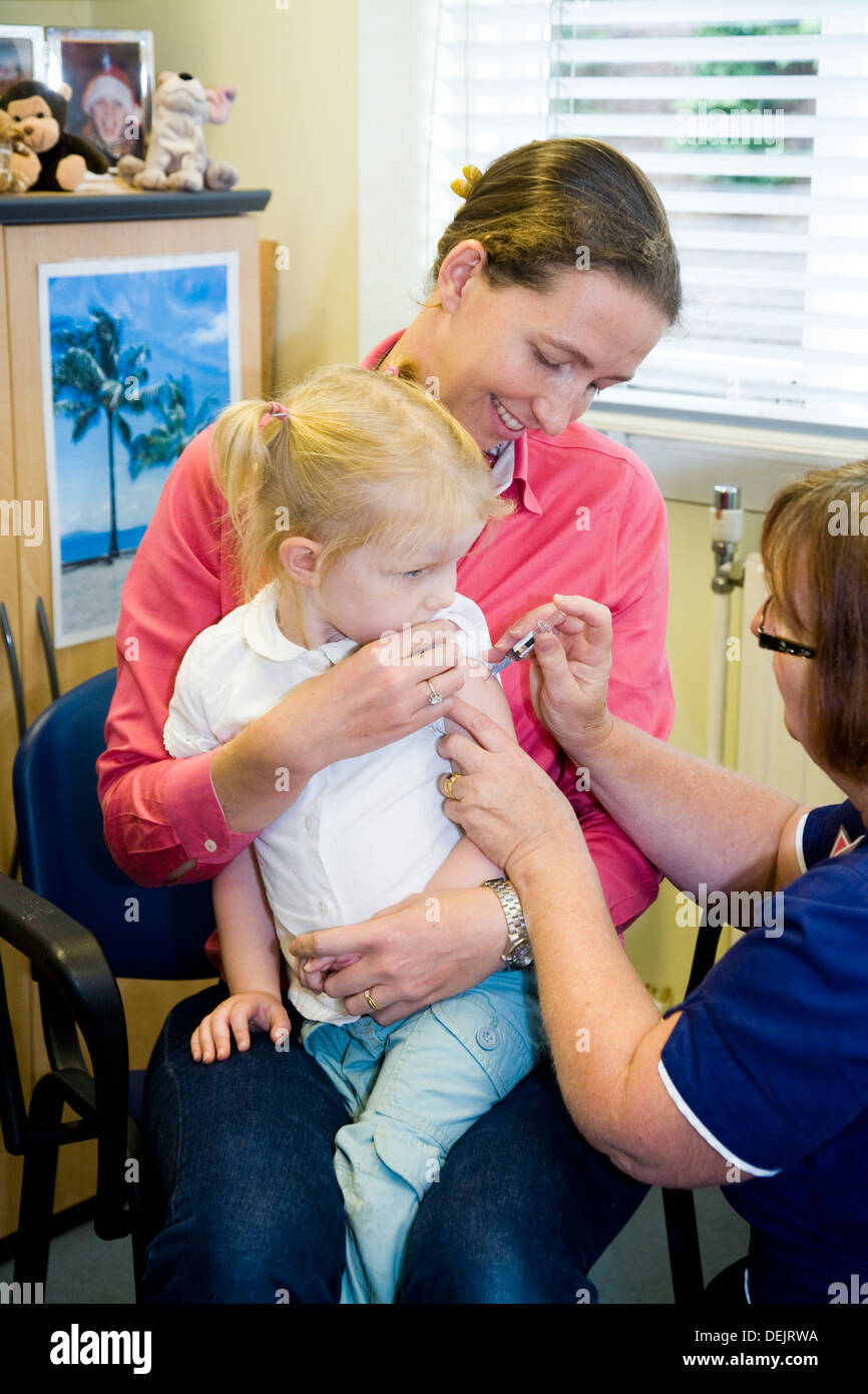 Nurse giving NHS 4-in-1 pre-school booster & MMR second dose immunisation / inoculation / jab to a three 3 year old child / girl Stock Photo