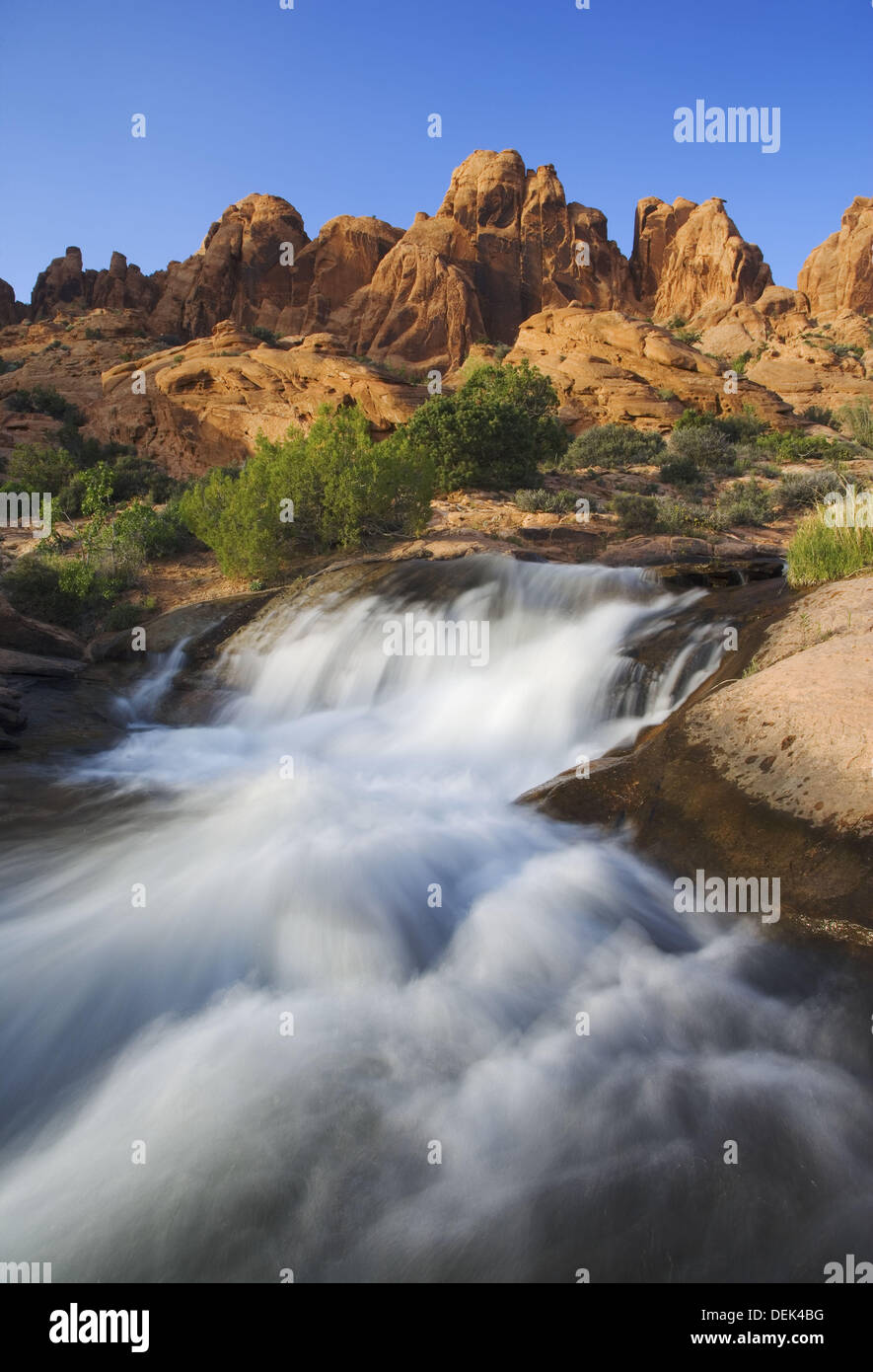 Snowmelt cascades over smooth sandstone below a rugged skyline near