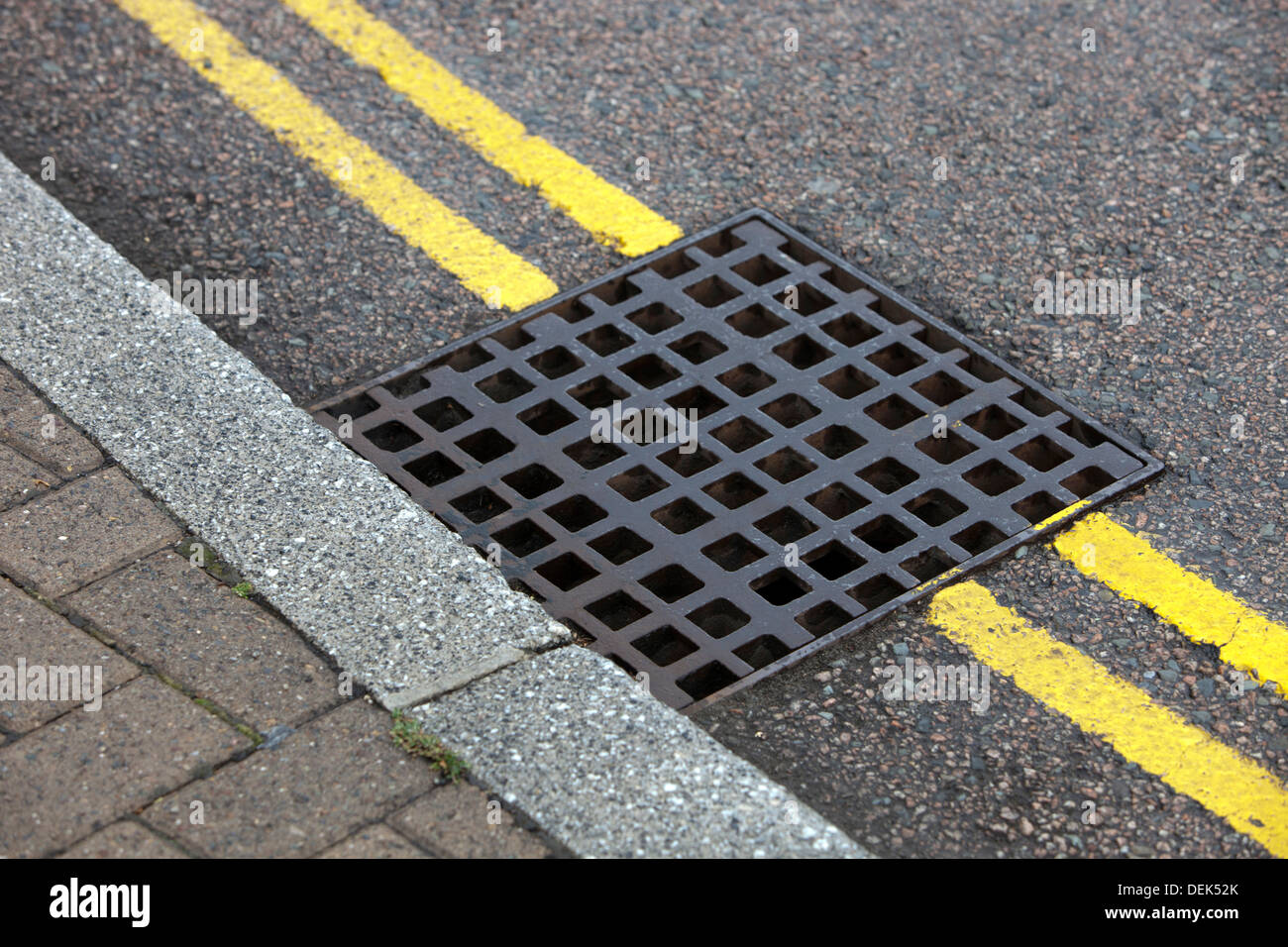 Street drain over Double yellow line on street Stock Photo