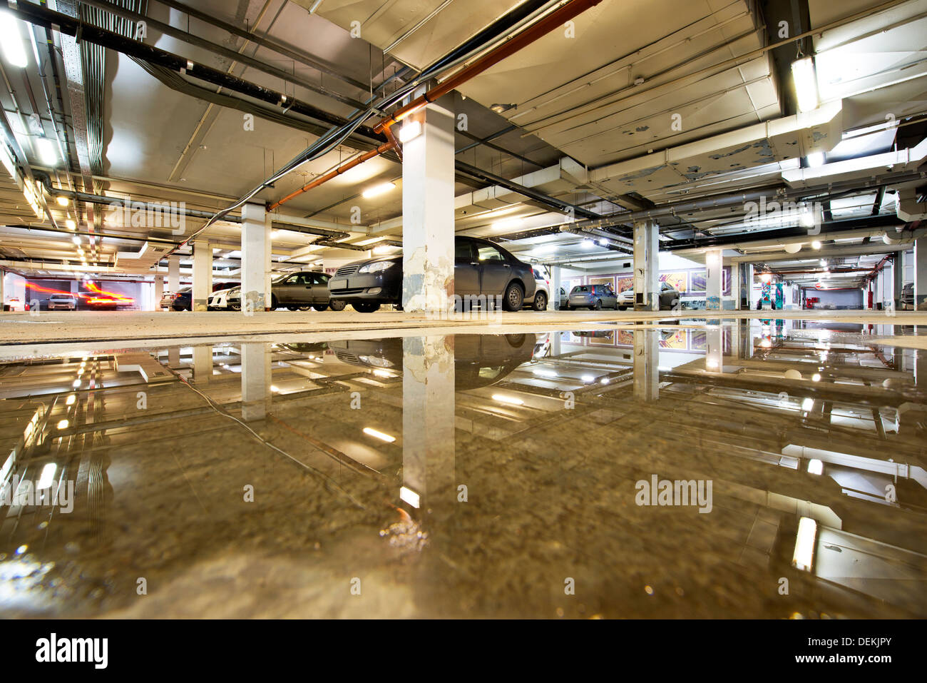 Ceiling reflected in wet parking structure floor Stock Photo