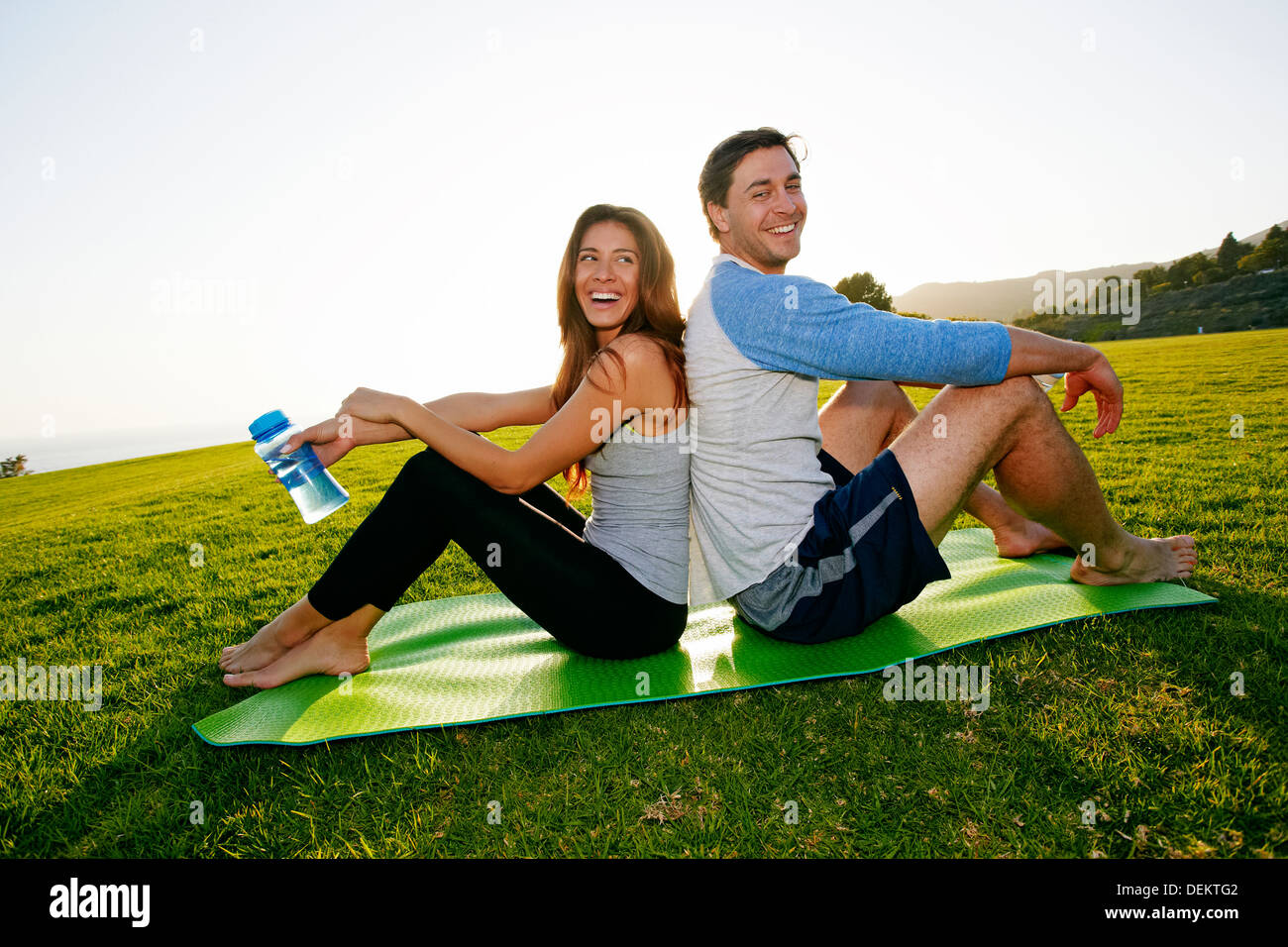 Couple sitting on yoga mat in park Stock Photo