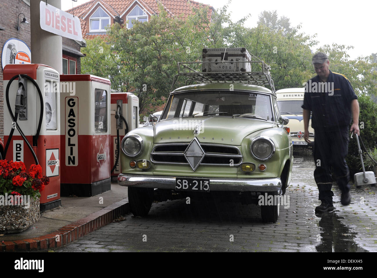Oldtimer specialist Volker Wischnewski walks through the rain with air compressor at his historic gas station in Bruchhausen-Vilsen, Germany, 20 September 2013. The station operator specializes in the repair and restoration of Borgward group vehichles. Photo: INGO WAGNER Stock Photo