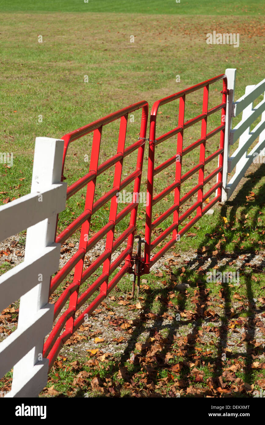 PADLOCKED RED GATE ON WHITE FENCE AROUND FARM FIELD Stock Photo